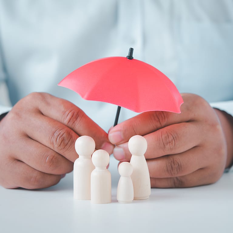 businessman's hand is holding an umbrella on the family tree. Businesses in human life, both health and family life.