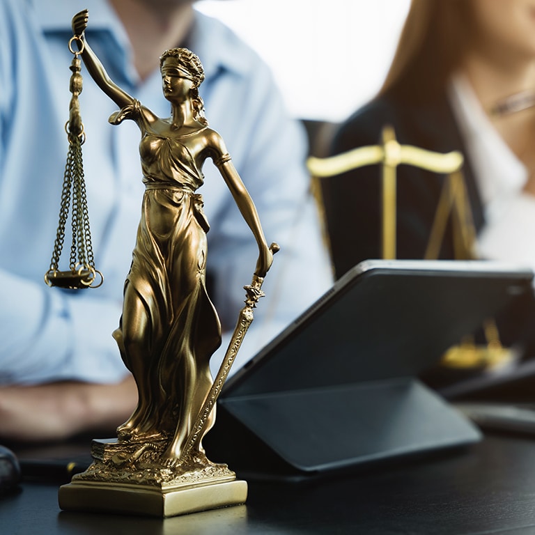 statue of justice with scales and auction hammer, the team meeting at the law firm behind the concept of in office law.