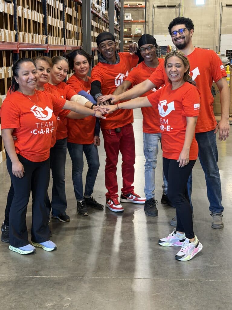 The LCP Care Team in the Warehouse doing a "Hands In" team huddle