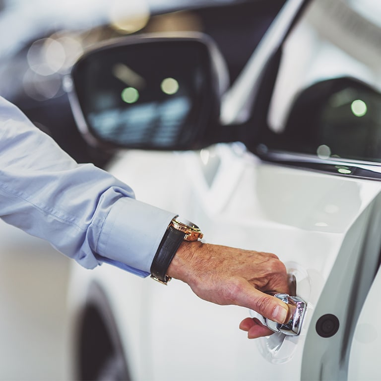 Middle aged businessman in classic shirt is opening a car in a motor show, close-up