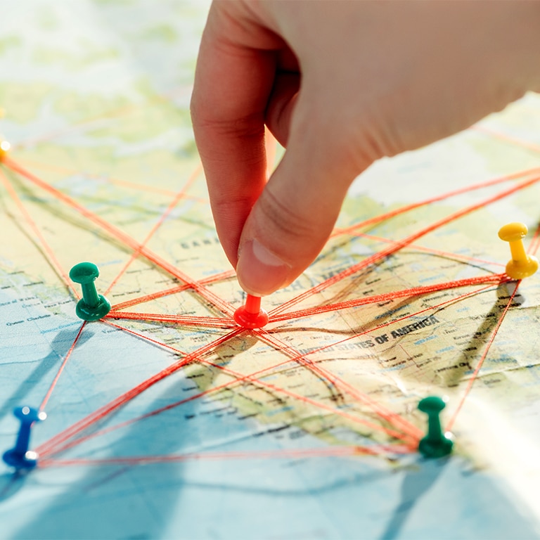 Partial view of woman with push pins, strings and world map